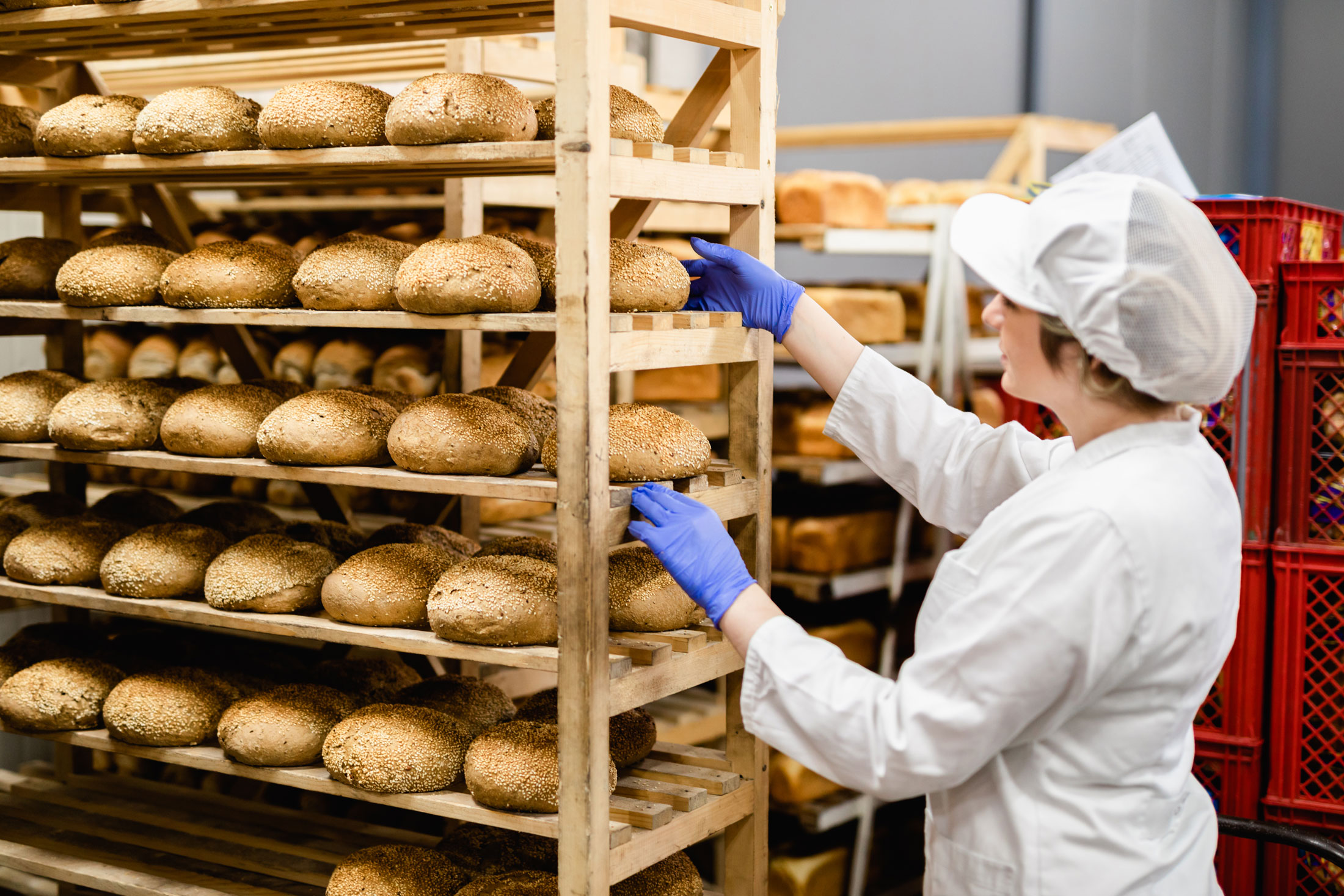 a woman organises a shelving unit filled with freshly baked bread