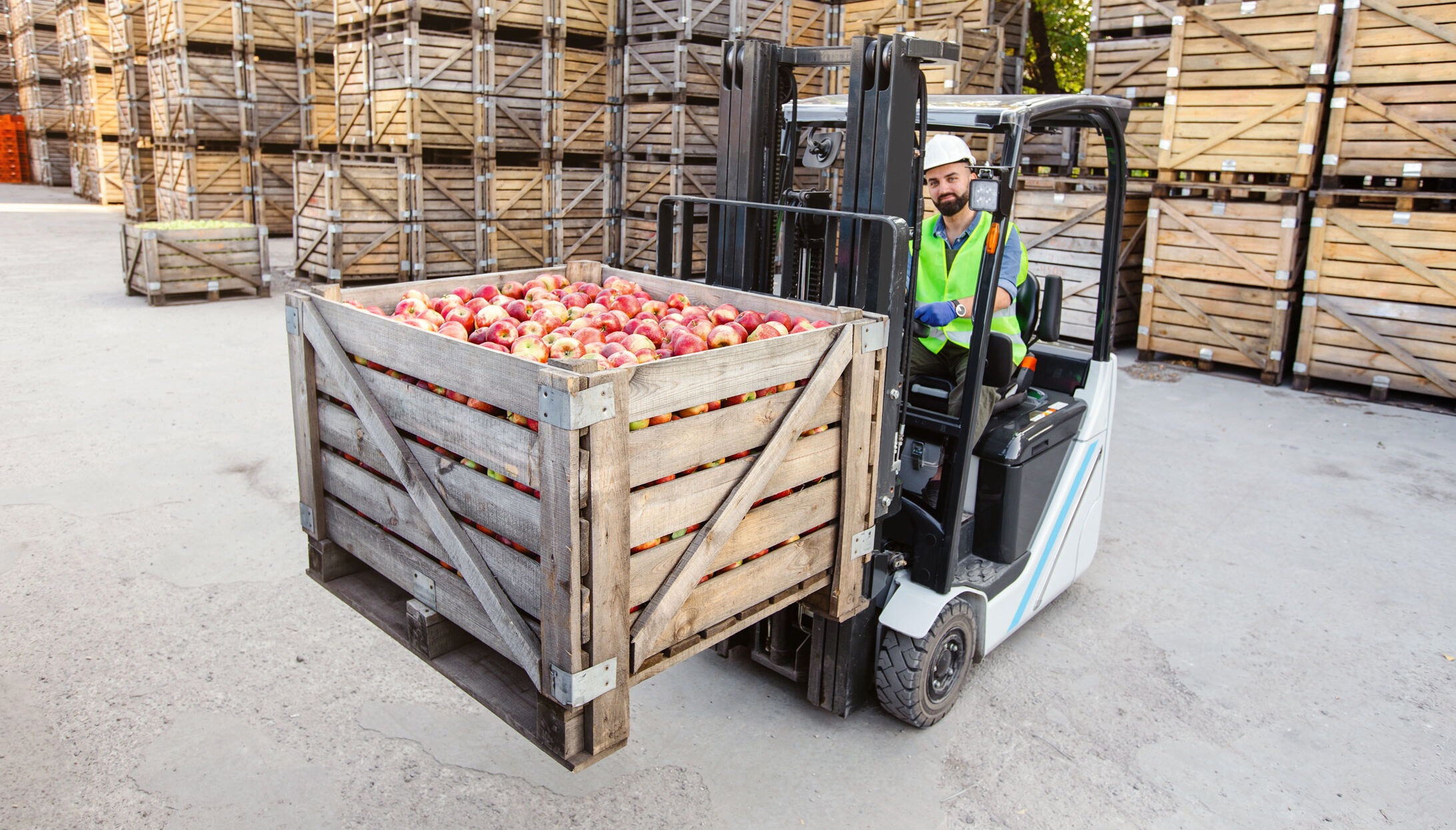man is moving supply box of apples using forklift